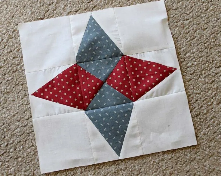 This Arkansas star block pattern would shine effortlessly on your quilt piece. It's a four-pointed star with a quarter-square triangle (QST) center. This block is also a great way to use up any fabric scraps you've got lying around.