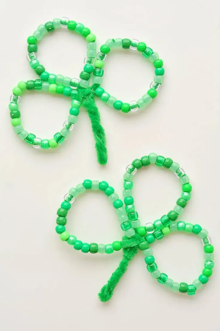 These precious beaded pipe cleaner shamrock charms will enthrall your kids and toddlers! This charming DIY project is an excellent way to add a touch of green around the house, and it could also be used as a charm bracelet.