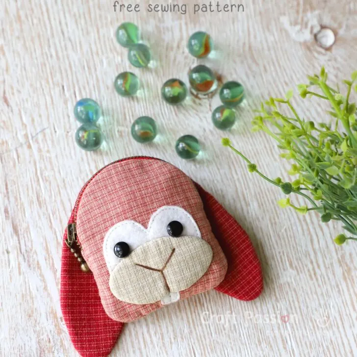 Free purse sewing pattern to sew an adorable bunny coin purse with zipper closure. A small bunny pattern purse with a pair of long ears in cherry color, in palm size.