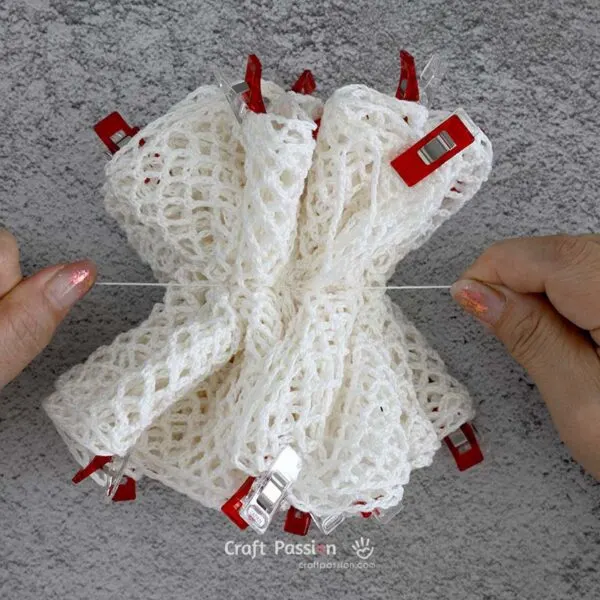 Gently pull the thread to gather the fabric and cinch it into a loofah shape.