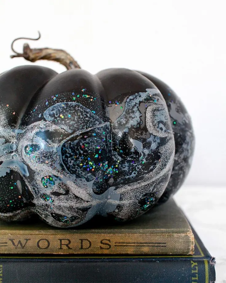 This iridescent design is definitely one of the most creative pumpkin painting ideas on this list! The supplies used are so normal. It uses only nail polish marbling, and the pumpkin is dipped in iridescent confetti and hologram glitter.