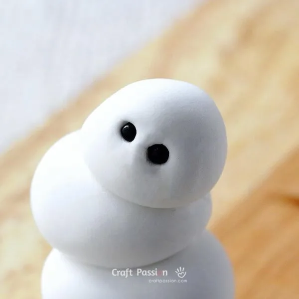 Press small beads into the top ball to form the snowman&rsquo;s eyes.