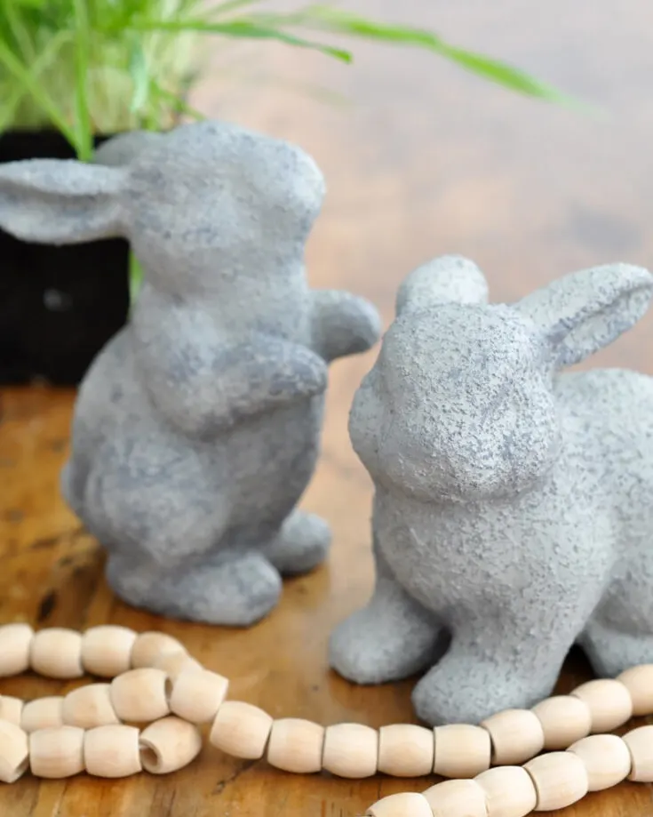 Looking to decorate your garden with a fun and cost-saving project? Try these faux cement bunnies! All you need are dollar store ceramic bunnies and cement paint finish. Now you can elevate your garden decor with this expensive looking decor.