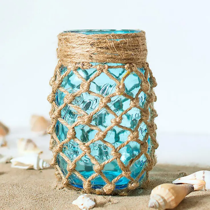 We love how the blue color pops out making a good contrast between the brown fishnet and the jar! This would go perfectly as a summer decoration. You can take it the next level by placing some sand around it too.