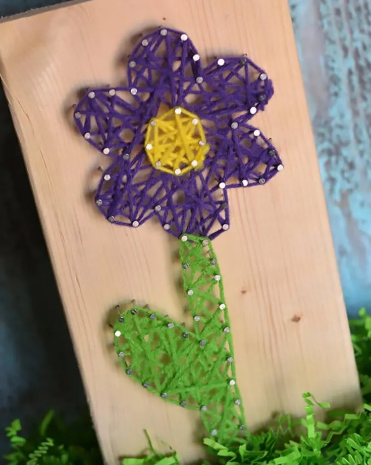Instead of using natural or faux flowers, how about creating vibrant blooms with a ball of yarn? This string art tutorial will teach you and your kids how to recreate this lovely design.
