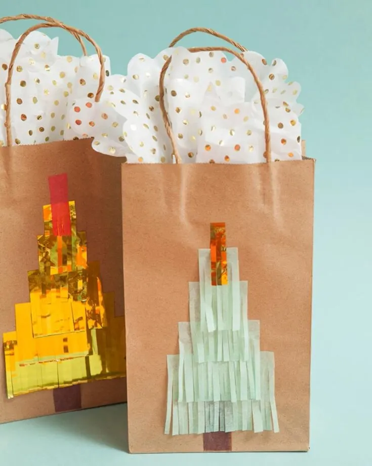 Check out these chic fringe Christmas tree gift bags! Simply layer colorful tissue paper cut into fringes to craft the cutest tree design, and voil&agrave;&mdash;your bags are holiday-ready!