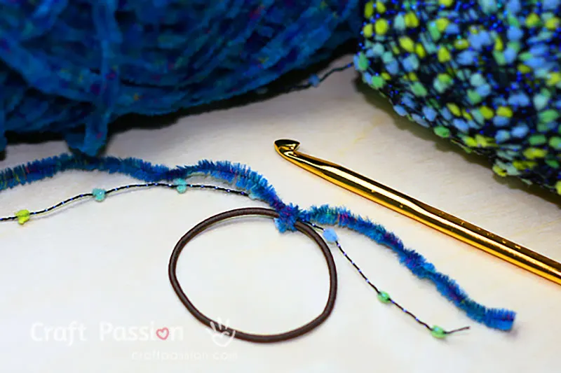 how to crochet scrunchie 
Step 1/5: fasten the yarn by tying a knot onto the rubber hairband.