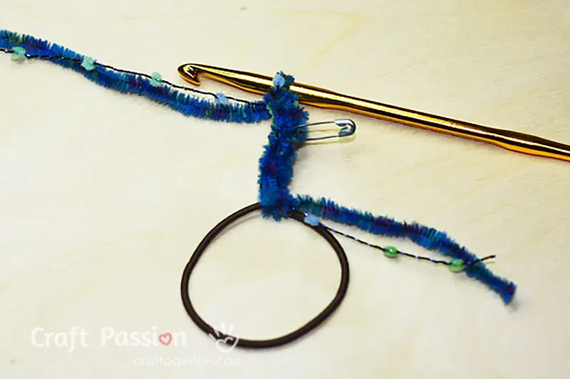 easy crochet scrunchie
Step 2/5: To start crocheting, insert the crochet hook under the elastic hairband, yarn over, and pull up a loop. Yarn over again, pull up a loop and pull it through the first loop. You are ready to crochet after connecting your crochet hook to the yarn and hairband.
Crochet 6 chains and mark the 3rd chain with a stitch marker.