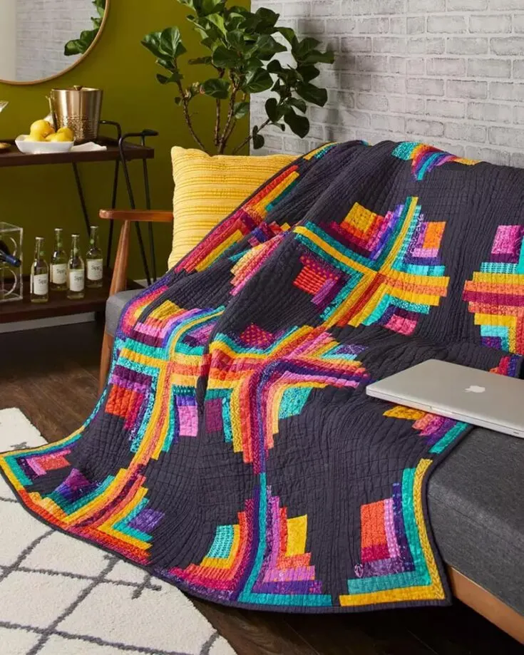 Taste the rainbow with this modern twist of a log cabin design! Inspired by a contemporary look, this pattern uses a dark background with saturated prints for an elevated quilt. If you&rsquo;re not a fan of the rainbows, feel free to use your favorite colored fabric strips instead. The finished size is 66 &frac12;&rdquo; x 77 &frac12;&rdquo;.