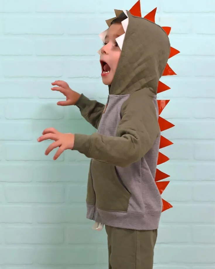 Roar! Make a rumbling entrance and roar into Halloween with this fantastic homemade no-sew dinosaur costume. Yes, you heard it right; it requires no sewing at all! This makes it the perfect craft for parents and children to participate in!