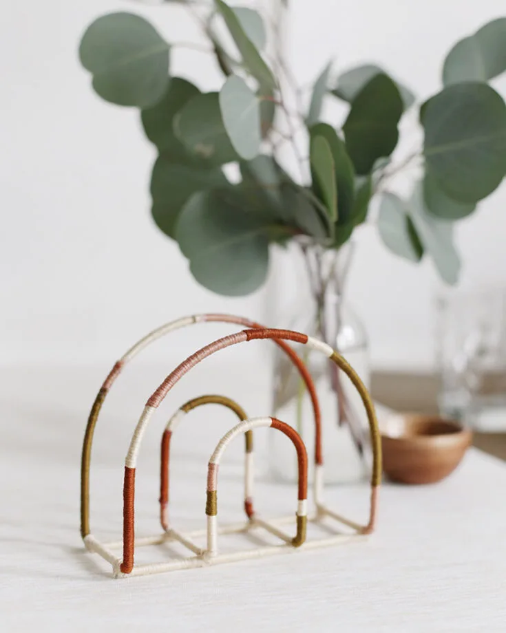 With modern colored rainbows being trendy in decor these days, transform this plain arched napkin holder from Dollar Tree wrapped strategically with colored embroidery floss during an afternoon dedicated to this crafting project. Now you can have your dinner guests pull out napkins out of this stylish holder.