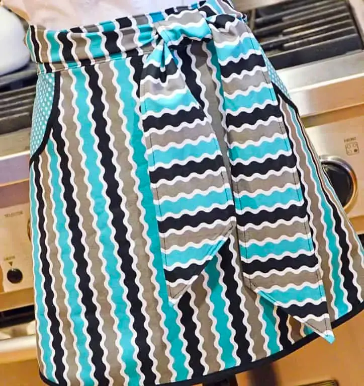 This washday chic waist apron is a simple knee-length apron that could go with any outfit! It's even brandished with two decorative patch pockets!