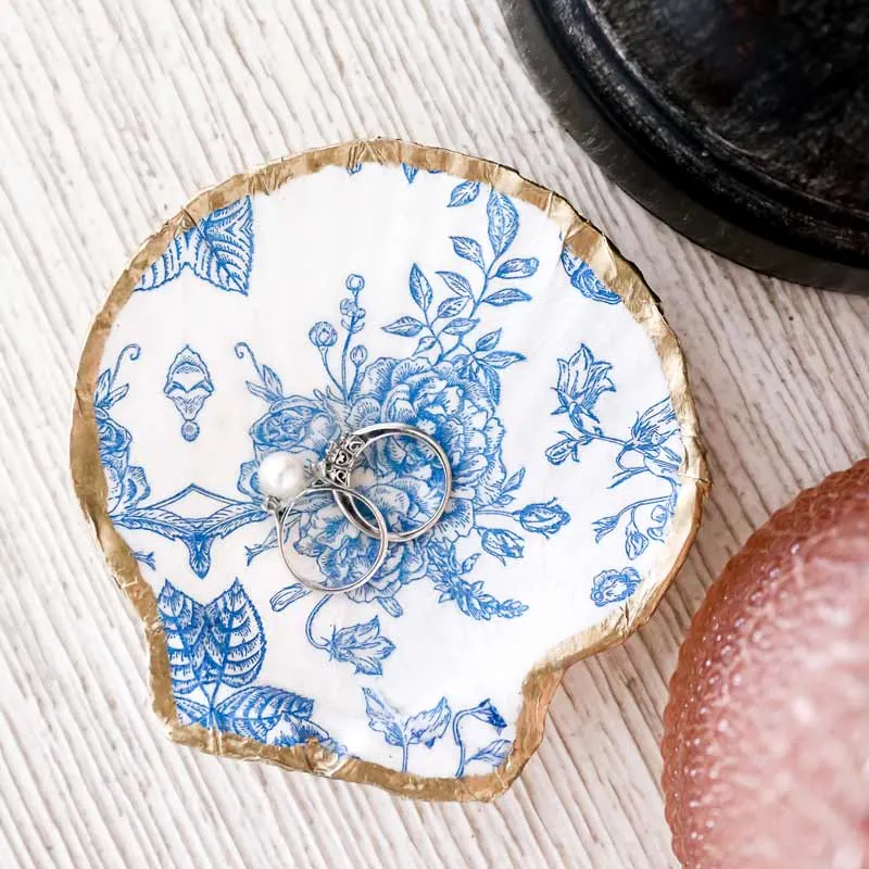 This seashell trinket dish is not only a great introduction to decoupaging for beginners but also adds a touch of elegance with its cute porcelain chinaware design and gold trim. Customize it with any napkin to create beautiful, personalized gifts for friends and family.