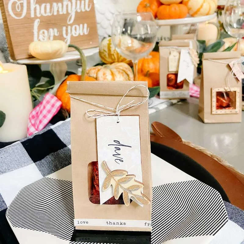 Planning a fall dinner? Why not elevate your gathering with Thanksgiving treat bag place cards featuring elegant gilded wooden embellishments? These treat bags not only seat your guests but also offer a sweet surprise for them to take home after the meal!