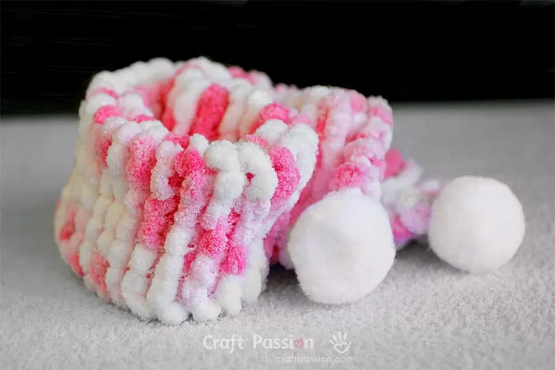 Learn how to make this easy chunky knit scarf by using pom-pom yarn. The free pattern comes with a video tutorial to show you the process.&nbsp;