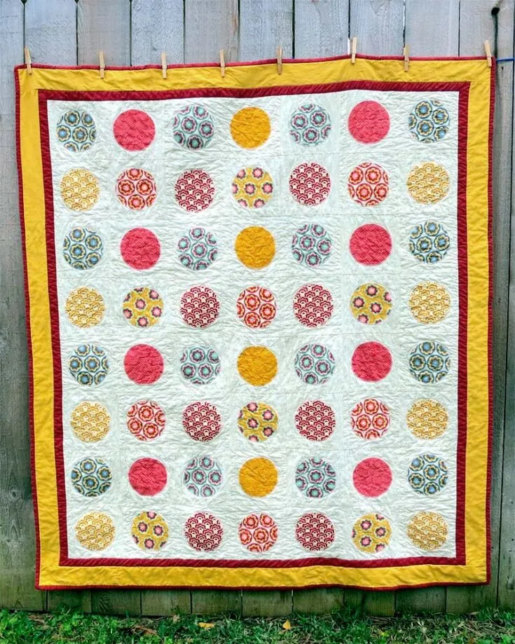 This 56" x 64" quilt pattern is reminiscent of the Billy Preston song 'Will It Go Round in Circles'. It's made of 56 circle appliques made from charm squares while the back is etched with a band of various layer cake strips. Please keep in mind that this pattern requires the use of a fusible web and a fabric cutter!